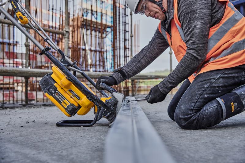 Una persona con equipo de seguridad de construcción utiliza una herramienta eléctrica inalámbrica DEWALT (SKU: DCPS330N) sobre una viga metálica en una obra.