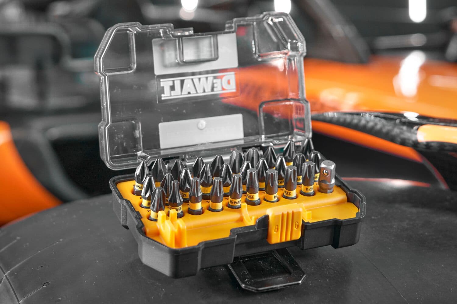 Un estuche de plástico amarillo y negro de la marca DEWALT que contiene un juego de puntas para destornillador, con la tapa transparente abierta y las puntas organizadas en su interior.
