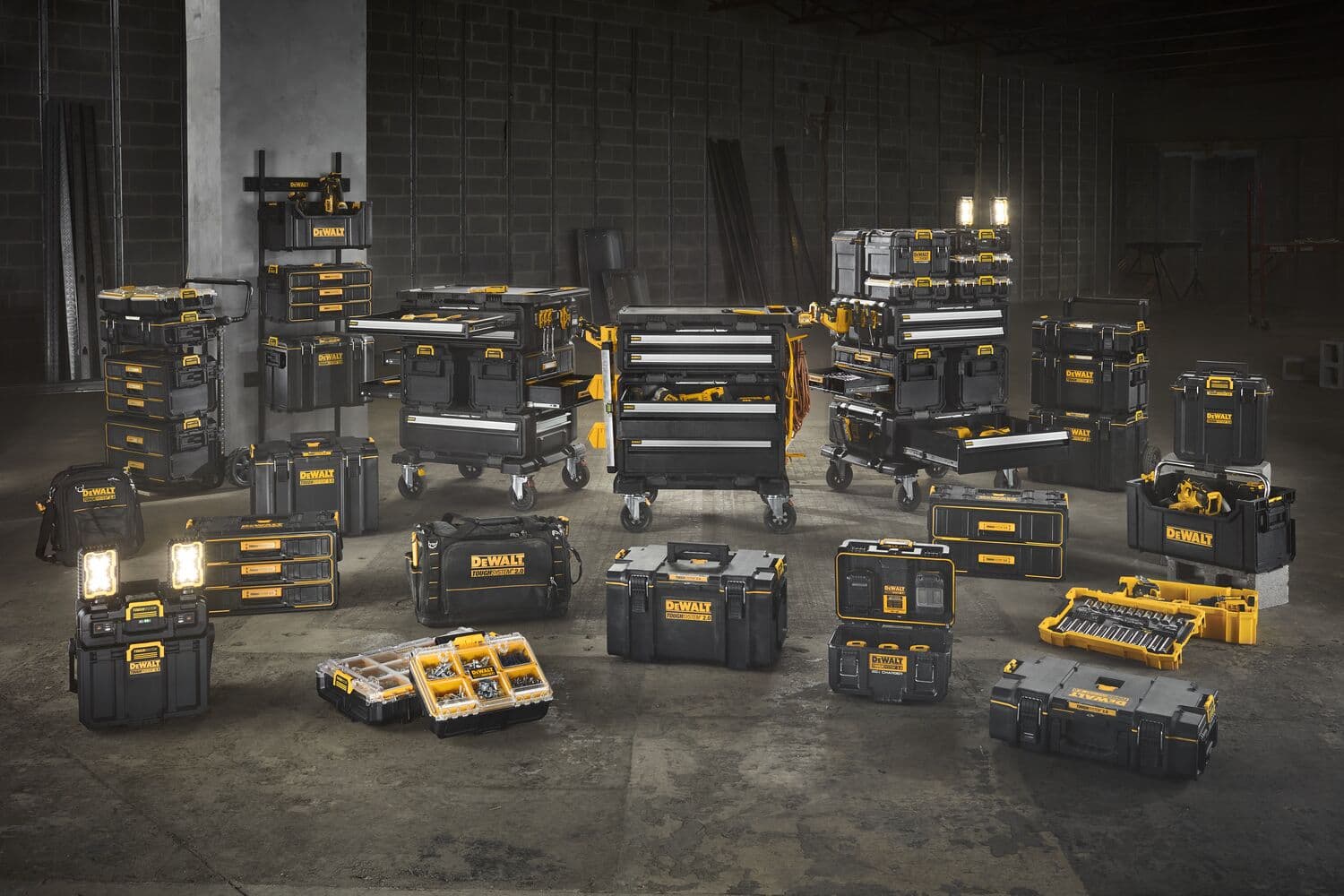 Varias cajas de almacenamiento de herramientas, organizadores y gabinetes rodantes de herramientas de la marca DEWALT en negro y amarillo están dispuestos en un almacén. Los productos se muestran en grupos, mostrando una variedad de cajas de herramientas, estuches portátiles, organizadores y luces de trabajo, destacando la versatilidad y capacidad de almacenamiento de las soluciones DEWALT.